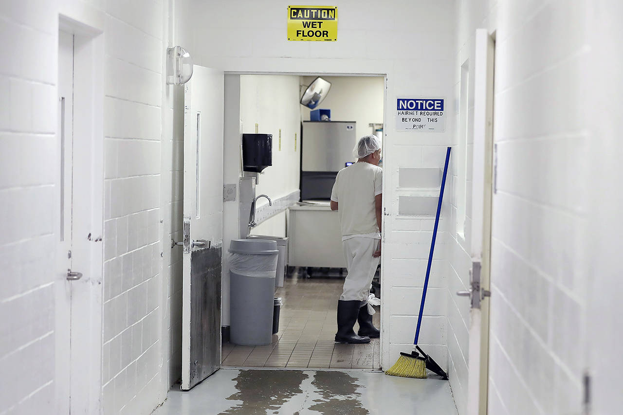 In this 2019 photo, a detainee works in a kitchen area at the GEO Group’s immigration jail in Tacoma. After nearly four years of litigation and pandemic-related delays, a federal jury on June 15 began deliberating whether the GEO Group must pay minimum wage to detainees who perform cooking, cleaning and other tasks at the facility – instead of the $1 per day they typically receive. (AP Photo/Ted S. Warren, file)