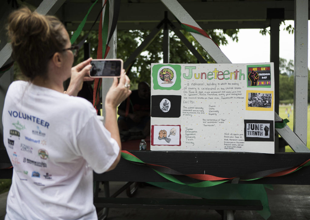 People stop to read and take photographs of Juneteenth information boards Saturday during the Justice to Jubilee Juneteenth Celebration in Monroe. (Olivia Vanni / The Herald)
