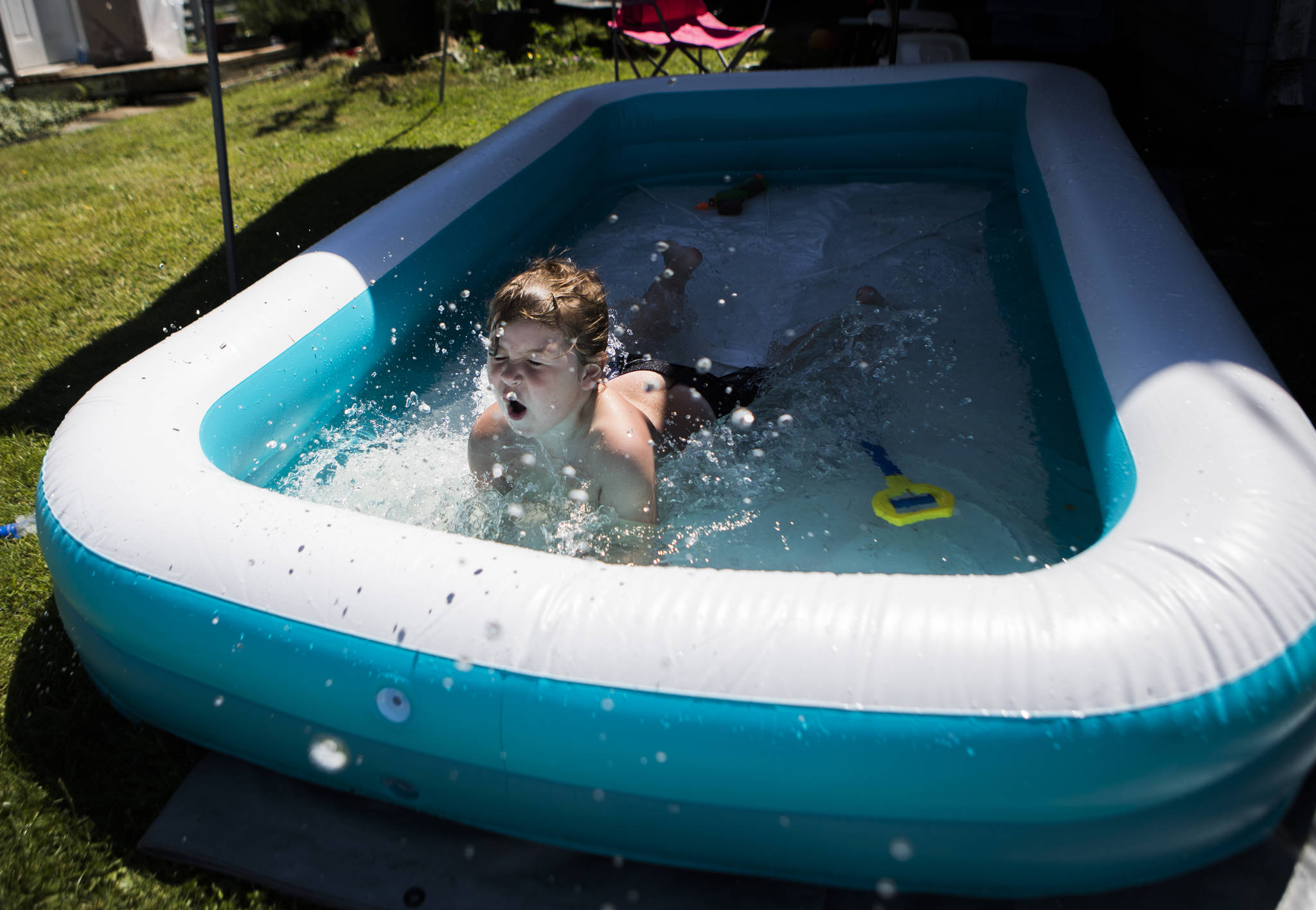 Adrian, 7, jumps into a pool in the yard of his home while enjoying the warm weather. (Olivia Vanni / The Herald)