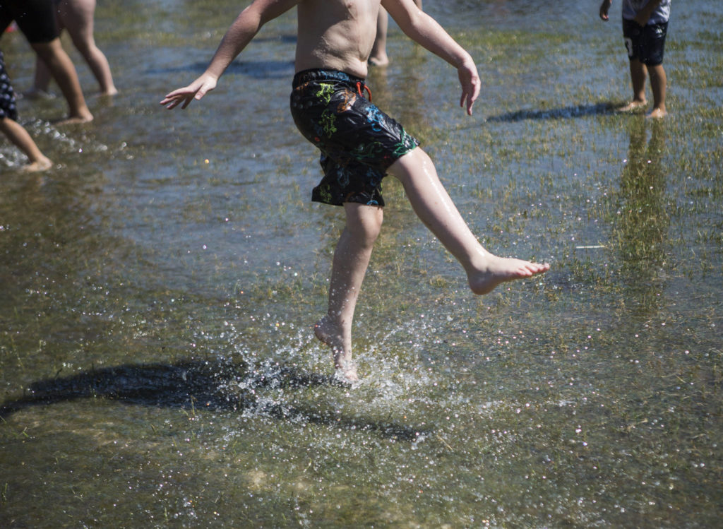 A child kicks up water in a large puddle Saturday at Walter E. Hall Park in Everett. (Olivia Vanni / The Herald)
