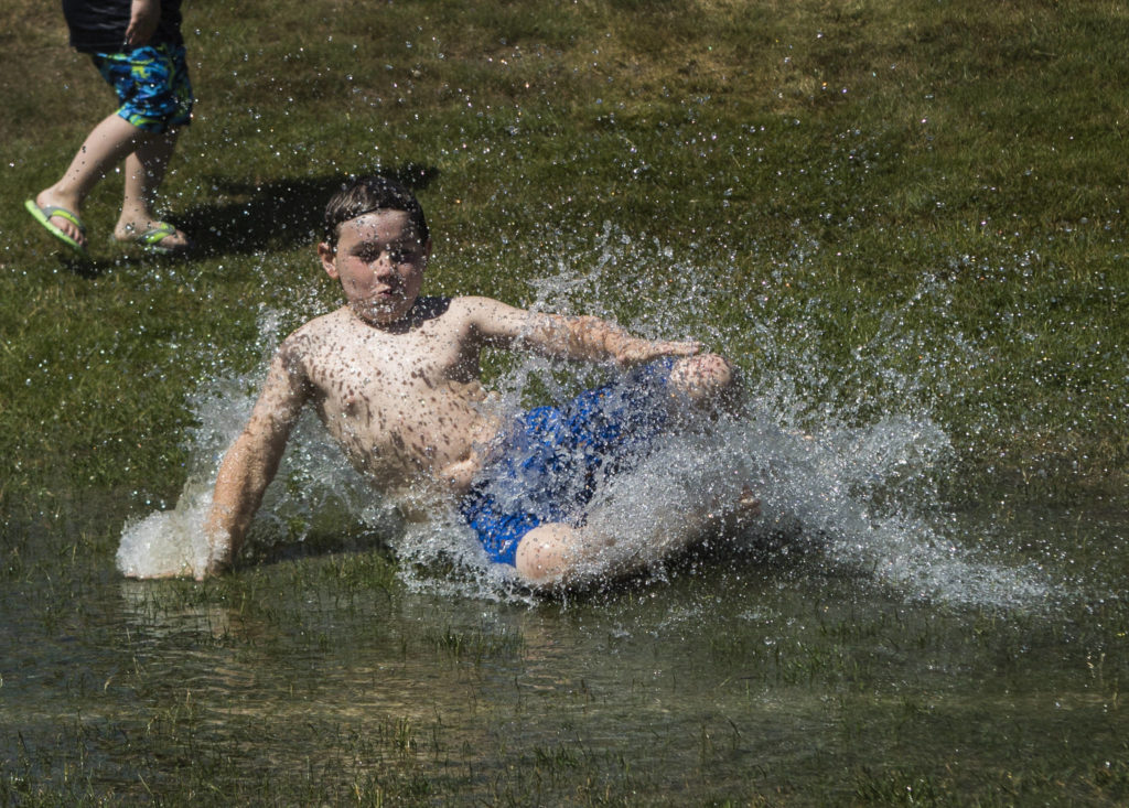 A boy slides into a large puddle Saturday at Walter E. Hall Park in Everett. (Olivia Vanni / The Herald)
