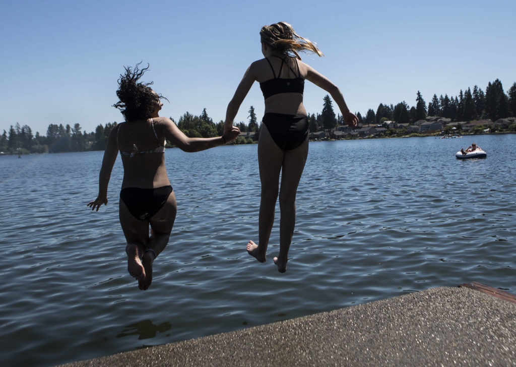 Brian McClenon, 14, left, and Nora Rates, 15, right, jump into Silver Lake at Thornton A. Sullivan Park in Everett on Saturday. (Olivia Vanni / The Herald)

