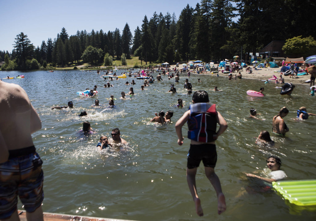 People swim and sit along Silver Lake’s beach Saturday at Thornton A. Sullivan Parkin Everett. (Olivia Vanni / The Herald)
