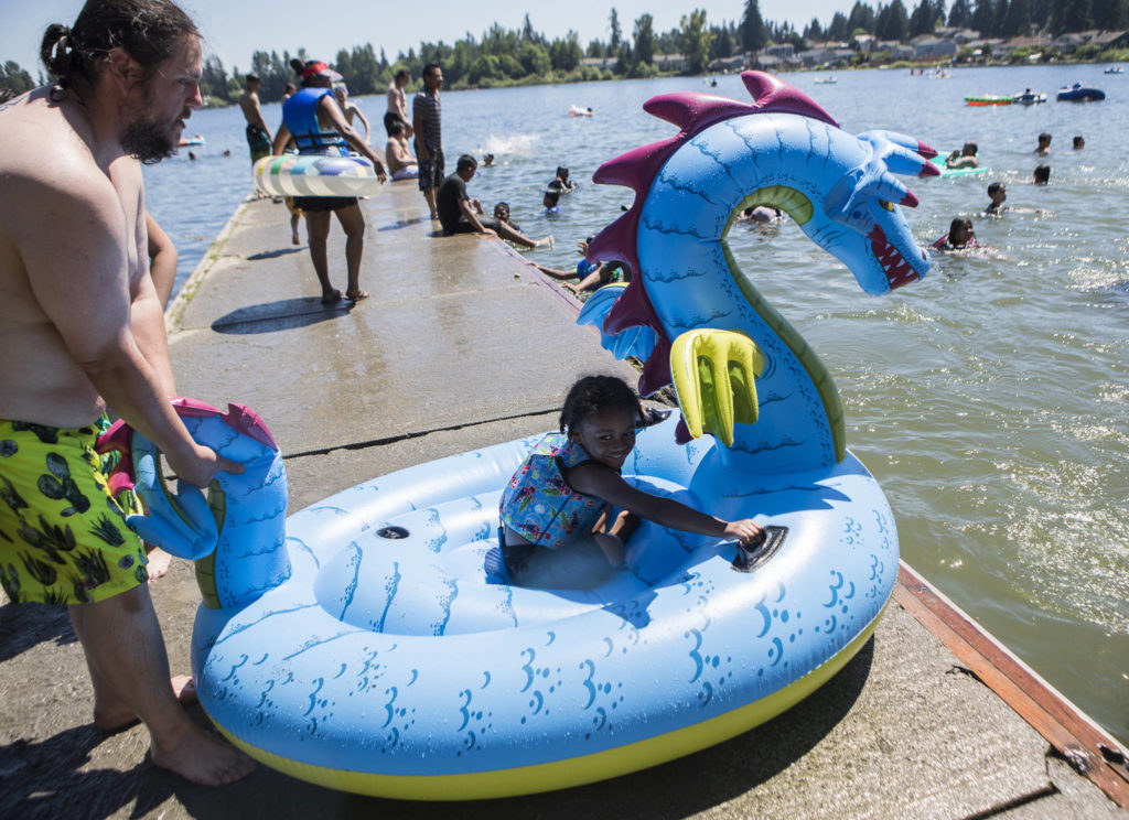 Derick Bradford pushes his son Warren, 5, into the water on his inflatable dragon Saturday at Thornton A. Sullivan Park in Everett. (Olivia Vanni / The Herald)
