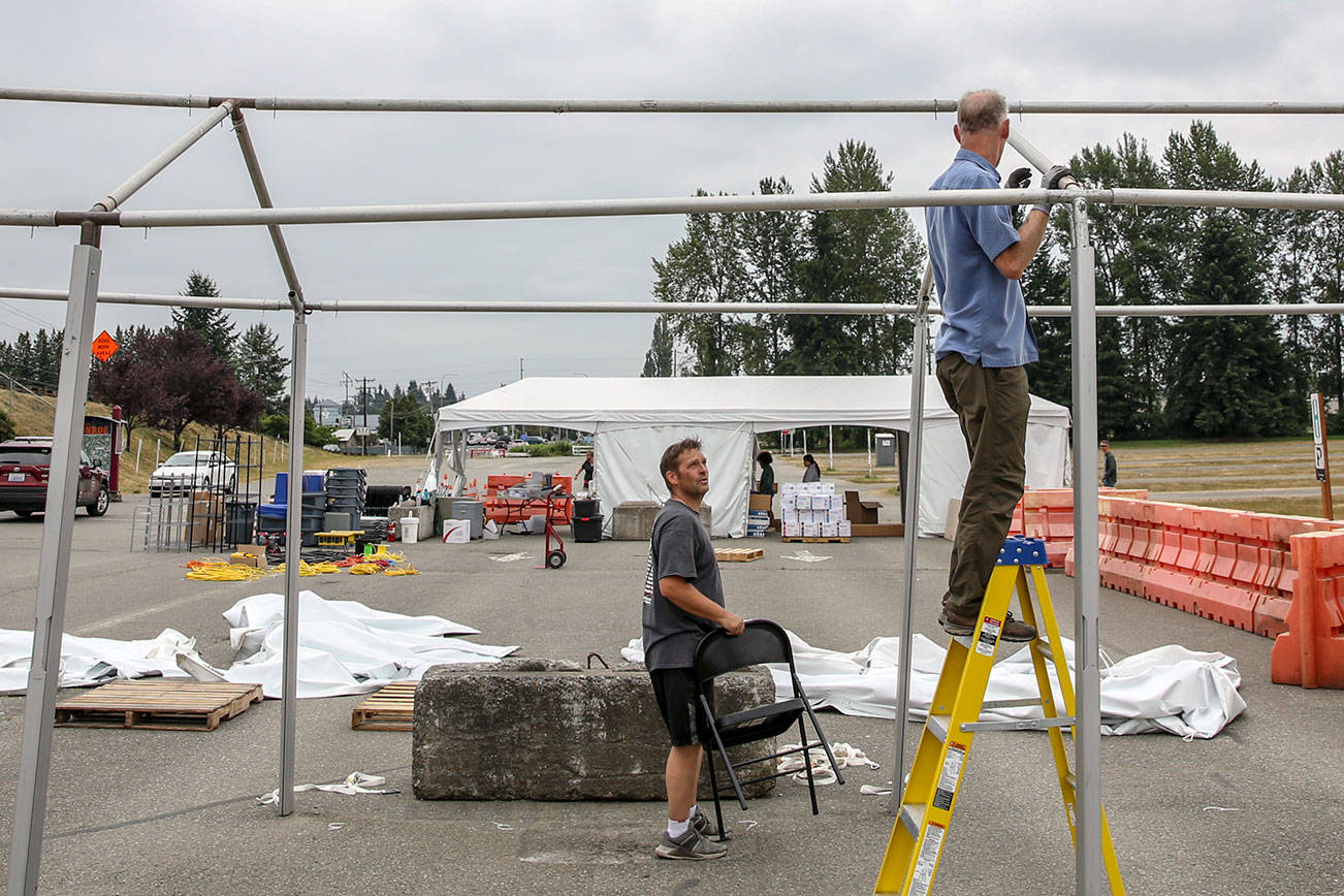 Jeff Irtter (left) and Tom Glasenapp work it dismantle a tent of the covid vaccination station Wednesday morning at the Evergreen State Fairgrounds in Monroe on June 30th, 2021. (Kevin Clark / The Herald)