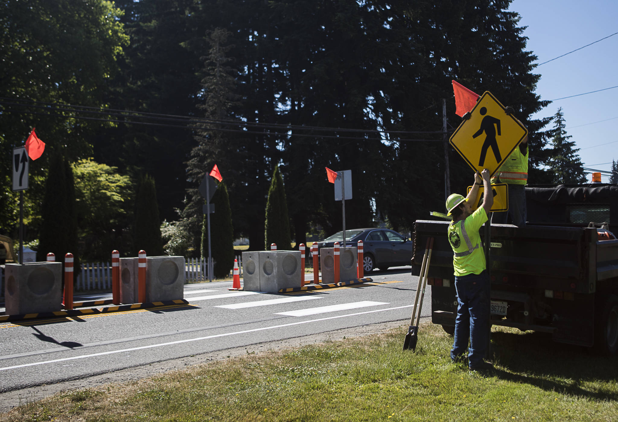 Arlington Public Works staff install a crosswalk sign at the corner of 180th Street NE and Smokey Point Boulevard in Arlington. The temporary changes are meant to slow traffic and encourage biking and walking. (Olivia Vanni / The Herald)