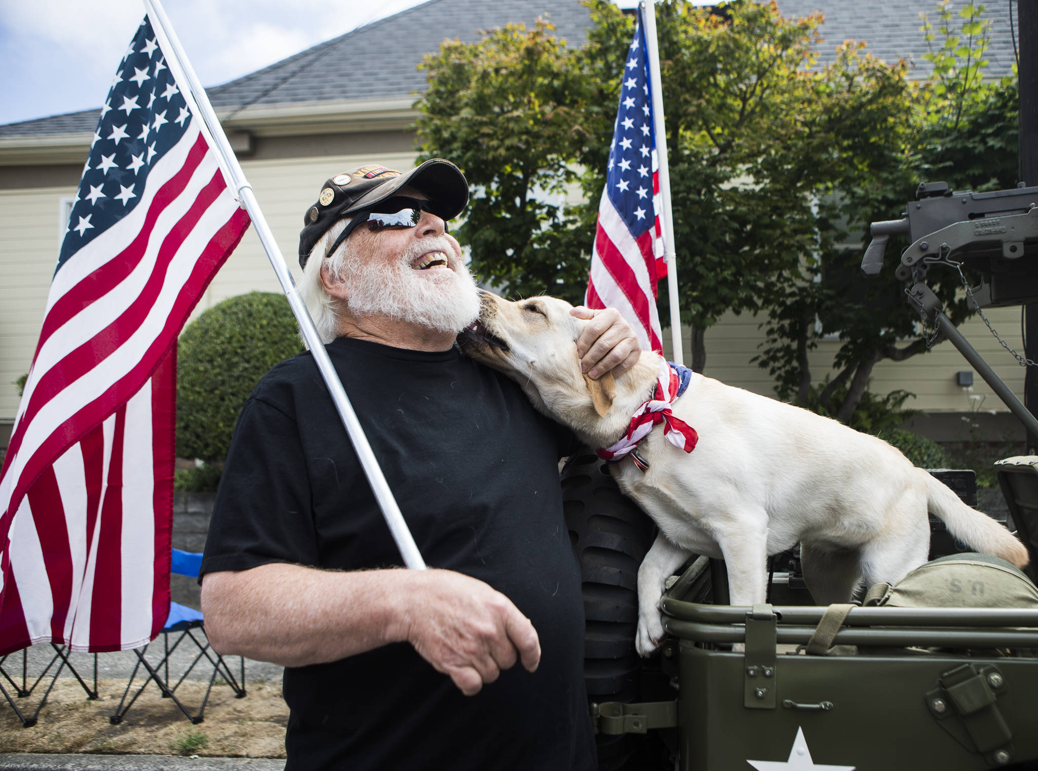Bob Little, a Vietnam War veteran, receives a kiss from a Labrador named Queso while waiting to walk in the “Edmonds Kind of 4th” parade with VFW Post 8870 on Sunday in Edmonds. (Olivia Vanni / The Herald)