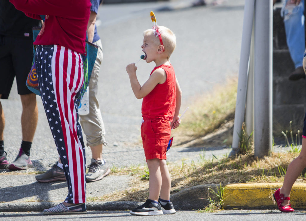 Aksel Young, 3, eats a lollipop while waiting for the “Edmonds Kind of 4th” parade on Sunday in Edmonds. (Olivia Vanni / The Herald)

