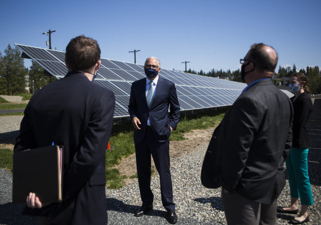 Gov. Jay Inslee stands in front of a line of solar panels that are a part of County PUD’s microgrid. (Olivia Vanni / The Herald)
