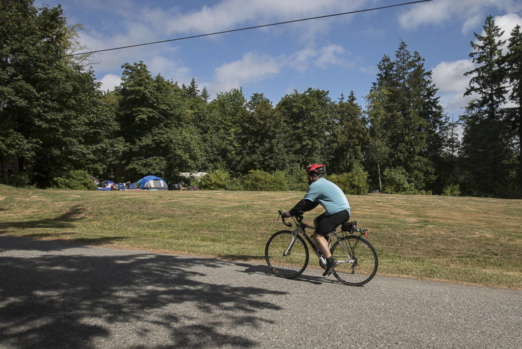 Ben Watanabe rides into Wenberg County Park on Saturday near Stanwood. The park is one of Snohomish County’s campgrounds and is, with great effort, technically reachable by bus and bike. (Olivia Vanni / The Herald)

