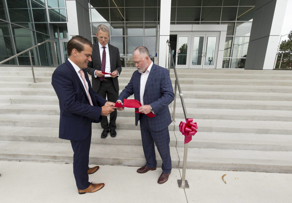 After cutting a section for Snohomish County Superior Court Judge George Appel, Joshua Dugan cuts off a piece of ribbon for Snohomish County Prosecuting Attorney Adam Cornell after the ceremony to mark the completion of the Snohomish County Courthouse remodel and addition project Thursday in Everett. (Andy Bronson / The Herald)
