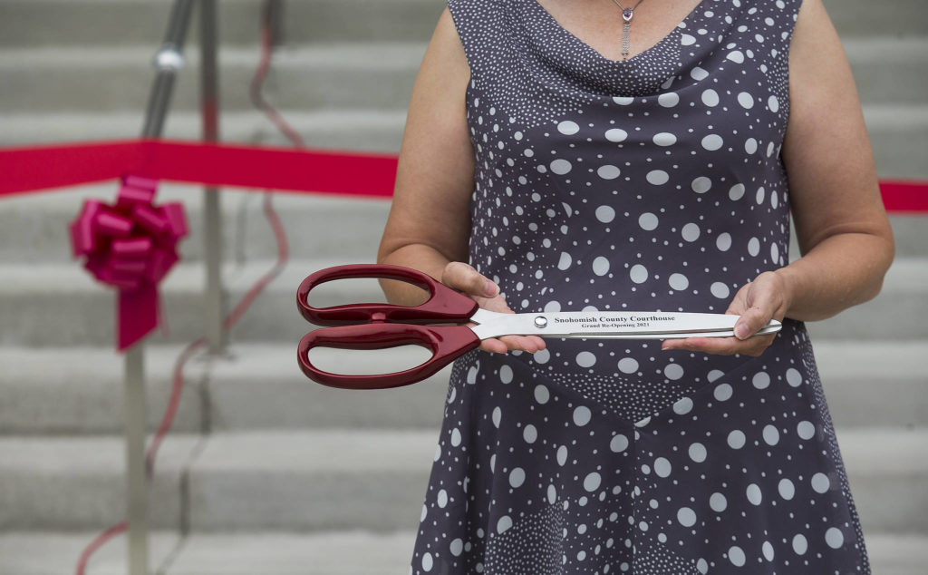Lolly Huggins holds commemorative scissors before a ribbon-cutting ceremony to mark the completion of the Snohomish County Courthouse remodel and addition project Thursday in Everett. (Andy Bronson / The Herald) 
