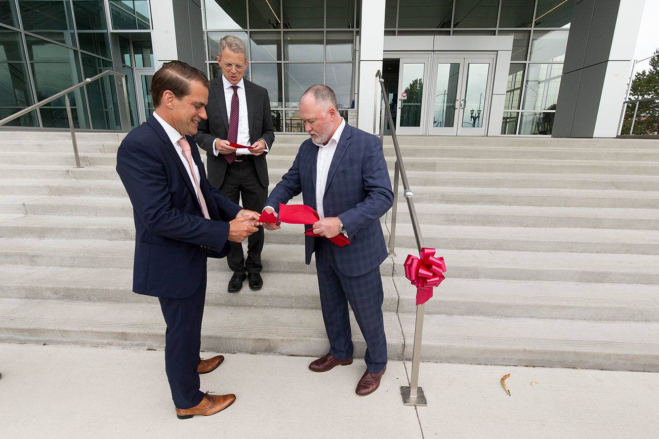 After cutting a section for Snohomish County Superior Court Judge George Appel, Joshua Dugan cuts off a piece of ribbon for Snohomish County Prosecuting Attorney Adam Cornell after the ceremony to mark the completion of the Snohomish County Courthouse remodel and addition project on Thursday, July 8, 2021 in Everett, Washington. The project started in 2017.  (Andy Bronson / The Herald)