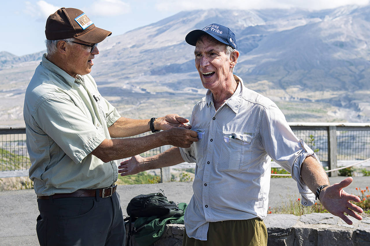 Gov. Jay Inslee (left) attaches a “Washingtonian” pin to and Bill Nye’s shirt during a visit to Johnston Ridge Observatory on Thursday at Mount St. Helens in Toutle. (Courtney Talak/The Daily News via AP)