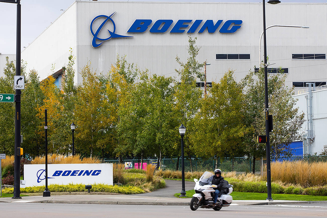 FILE - In this Oct. 28, 2020 file photo, a motorcyclist cruises past the Renton, Wash., Boeing plant where 737's are built. Boeing is temporarily lowering its delivery target for the 787 Dreamliner after discovering additional work that will need to be performed on the aircraft. The company said Tuesday, July 13, 2021, that the 787 production rate will temporarily be lower than five per month and will gradually return to that rate. (Ellen M. Banner/The Seattle Times via AP, File)