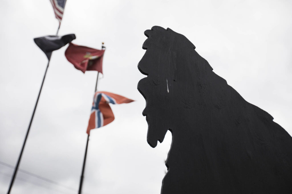 Nathaniel Lindell’s Bigfoot cutout in Everett stands below the U.S. Marine Corps flag, the flag of Norway, the American flag and the POW/MIA flag. (Olivia Vanni / The Herald)
