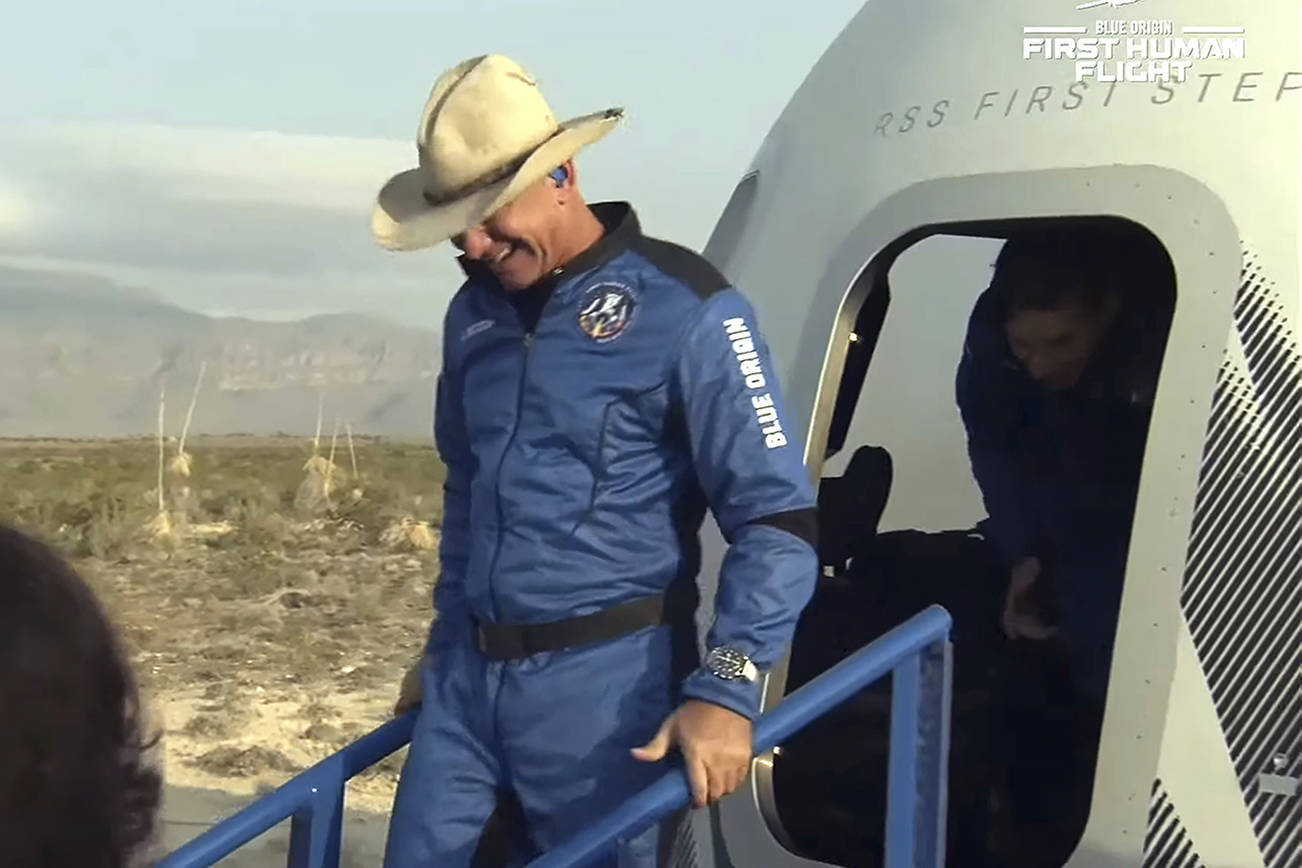 This photo provided by Blue Origin,   Jeff Bezos, founder of Amazon and space tourism company Blue Origin, exits the  Blue Origin's New Shepard capsule after it parachuted safely down to the launch area with passengers Mark Bezos, Oliver Daemen and Wally Funk, near Van Horn, Texas, Tuesday, July 20, 2021.  (Blue Origin via AP)