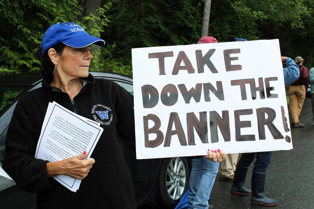 Maureen Greene displays a sign and distributes informational papers opposing the Black Lives Matter banner at a June 11 protest. (Karina Andrew / Whidbey News-Times)
