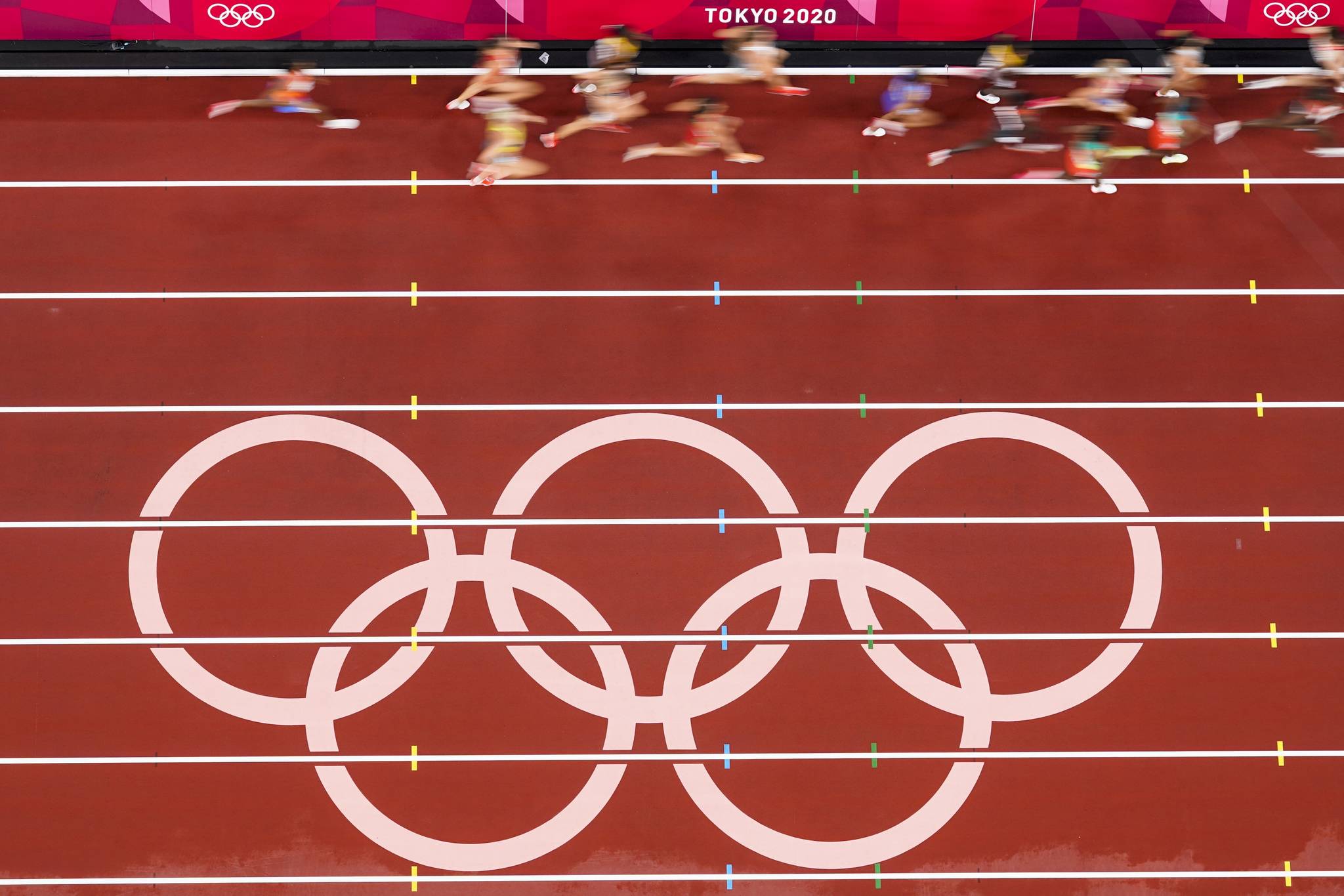 Runners pass the Olympic rings as they compete during the first round of the women’s 5,000-meter at the 2020 Summer Olympics on Friday in Tokyo. (AP Photo/Morry Gash)