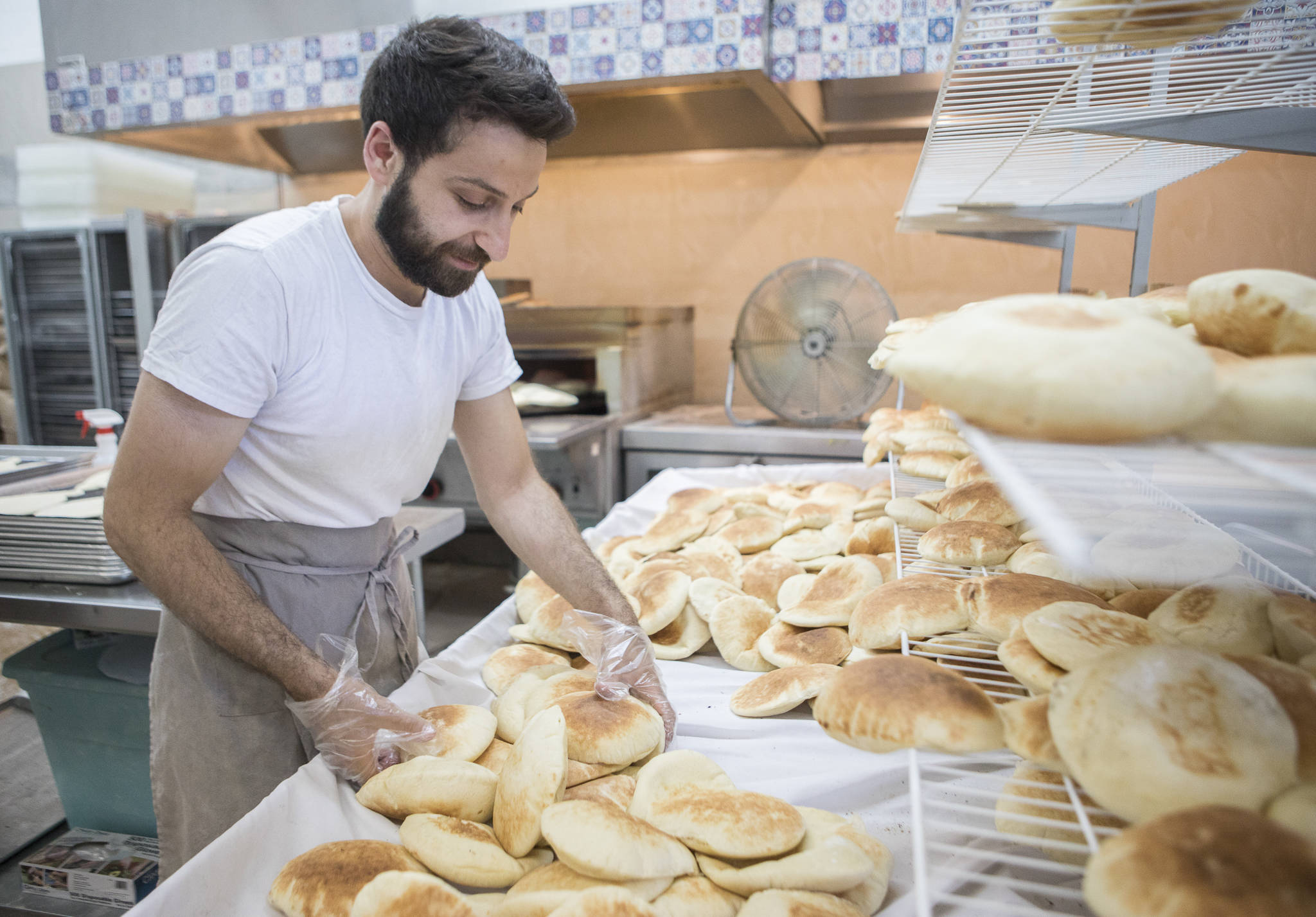 Nechirvan Zebari sorts through freshly made pita bread at Alida’s Bakery in Everett. (Olivia Vanni / The Herald)