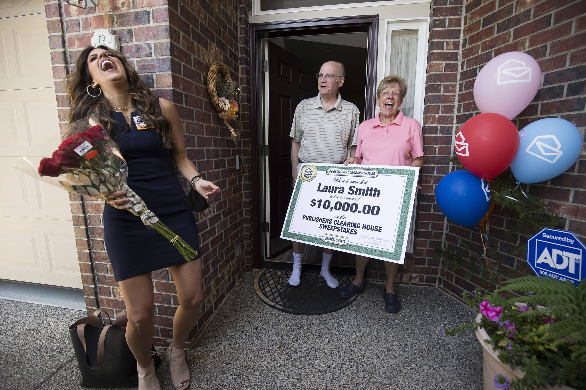 Laura Smith and her husband, Tom, make Danielle Lam laugh after she surprises them with a check for $10,000 from the Prize Patrol from Publishers Clearing House at their Mukilteo home. (Andy Bronson / The Herald)