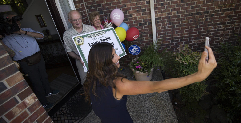 As photographer Geoff Dunlap records video, Danielle Lam takes a selfie with Mukilteo winner Laura Smith and her husband, Tom. Laura Smith won $10,000 from the Publishers Clearing House Prize Patrol. (Andy Bronson / The Herald)
