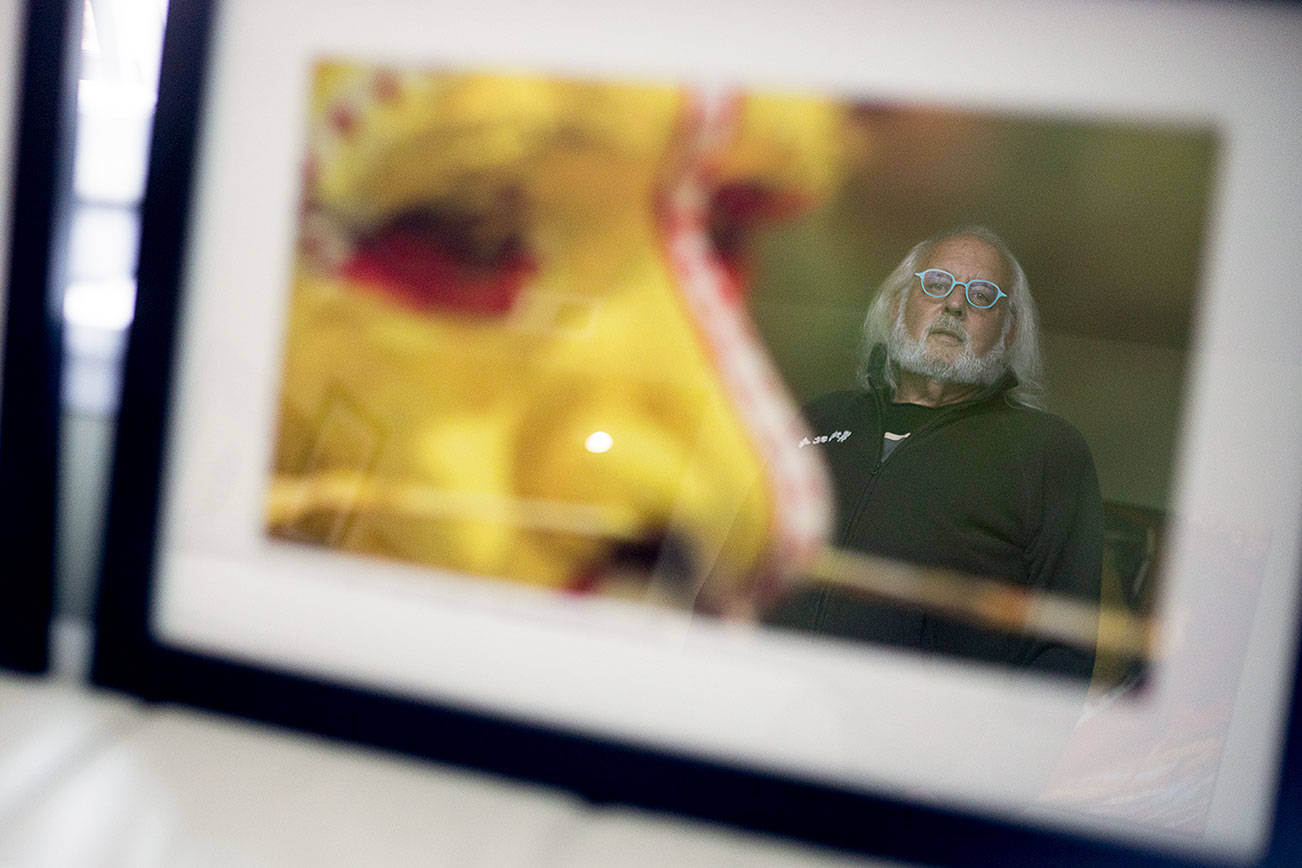 Bob Fink, reflected in one of his photographs, at his home on Saturday, July 31, 2021 in Everett, Wash. (Olivia Vanni / The Herald)