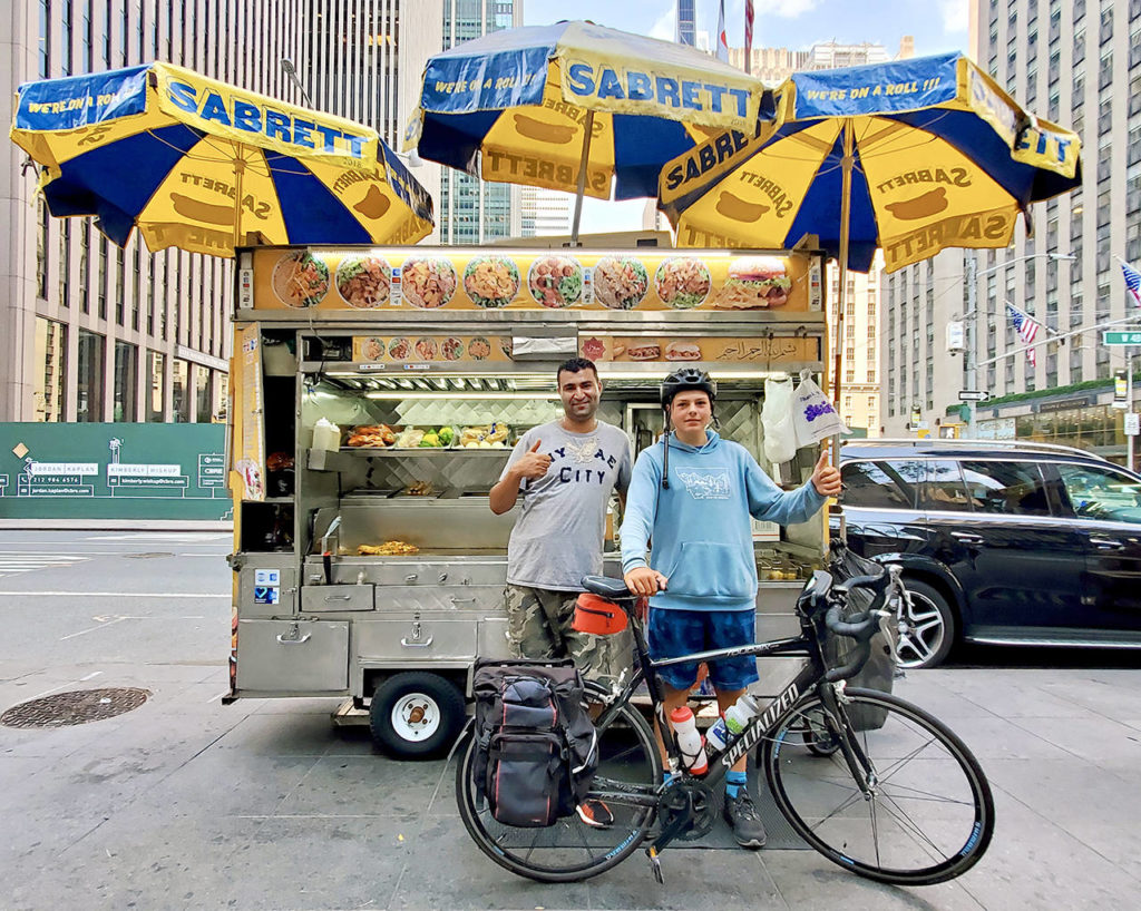 Deven Boyce gets a hot dog in New York City after many days of eating cups of noodles and green beans from a can during a 3,000-mile cross-country bike ride from Mukilteo. (Submitted photo)

