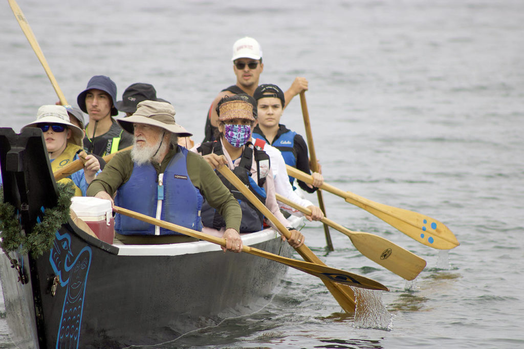 Blue Heron Canoe Family paddlers back away from the shore in front of the Edmonds Waterfront Center, beginning their two week journey to Lummi Island. (Isabella Breda / The Herald)
