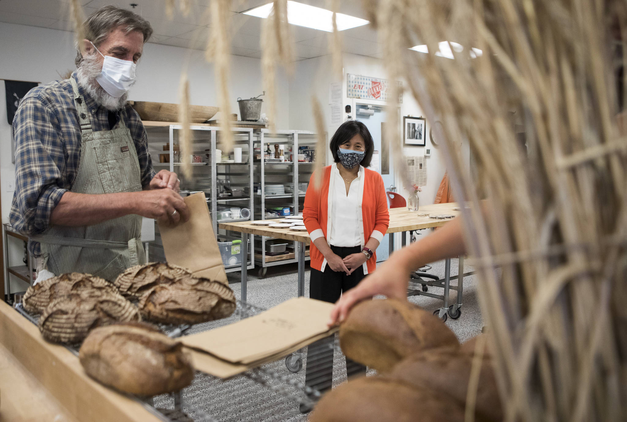 Stephan Jones (left), director of the Washington State University Bread Lab, packages loaves for U.S. Trade Representative Katherine Tai (center) at the end of her tour on Thursday in Burlington. (Olivia Vanni / The Herald)
