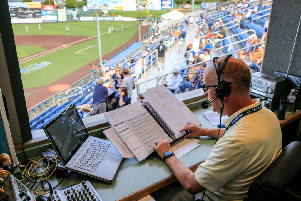 AquaSox broadcaster Pat Dillon calls the action on the field during a game against the Emeralds on July 28, 2021, at Funko Field in Everett. (Kevin Clark / The Herald)
