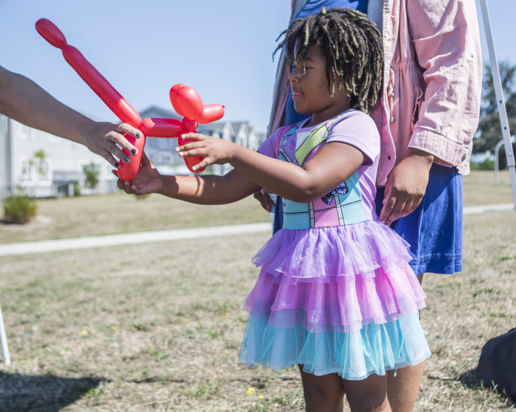 Maylani Moore receives a red balloon dog from ballon artist Sara Lynn at the Delta Art Experience at Henry M. Jackson Park in Everett. (Olivia Vanni / The Herald)
