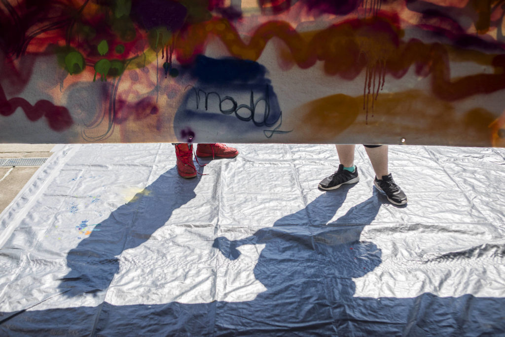 People spray paint on a mural hosted by JAG Artworks during the Delta Art Experience on Sunday in Everett. (Olivia Vanni / The Herald)
