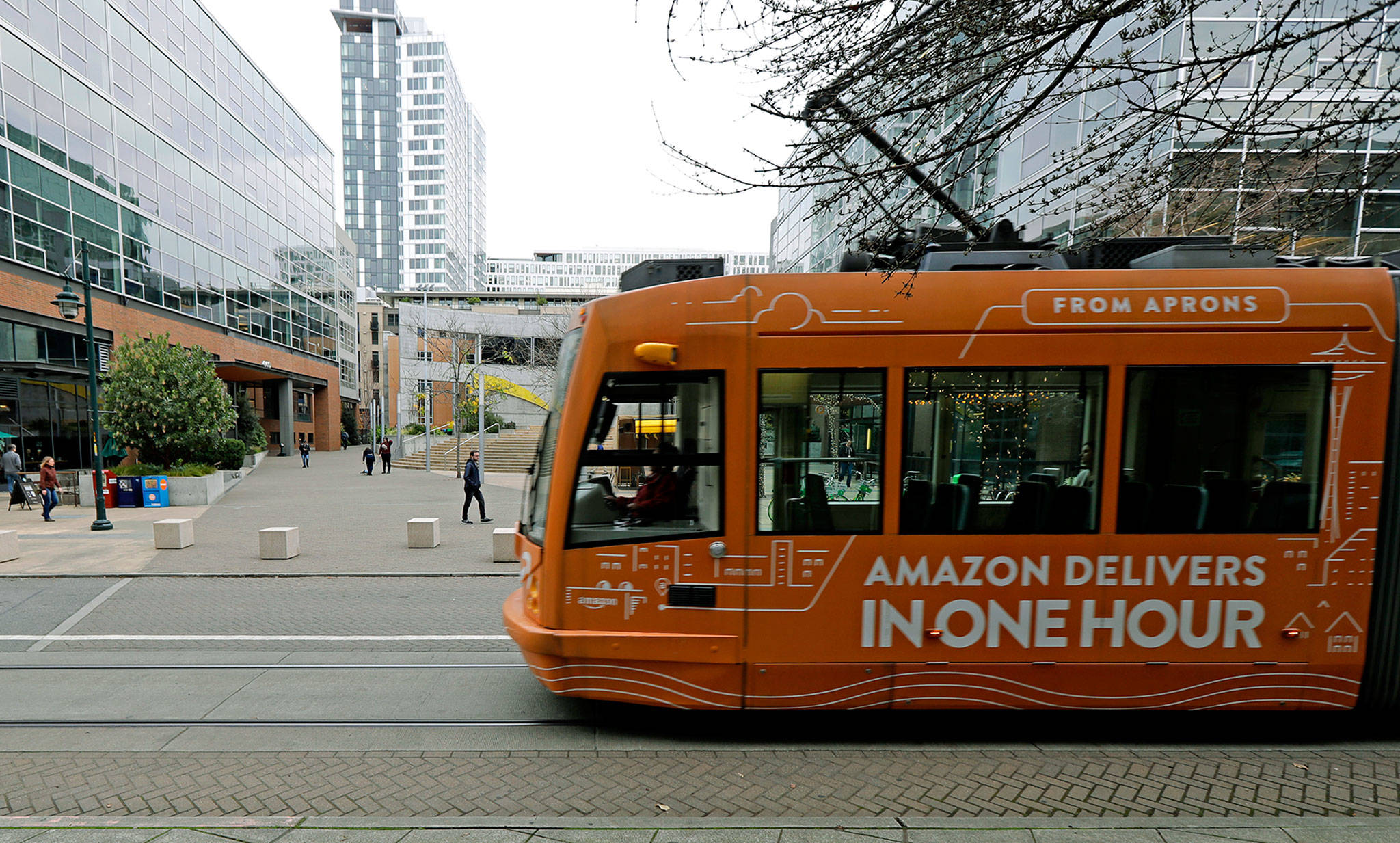 A South Lake Union streetcar with an advertisement for Amazon.com’s same-day delivery service passes by an Amazon office building in Seattle’s South Lake Union neighborhood. (AP Photo/Ted S. Warren,File)