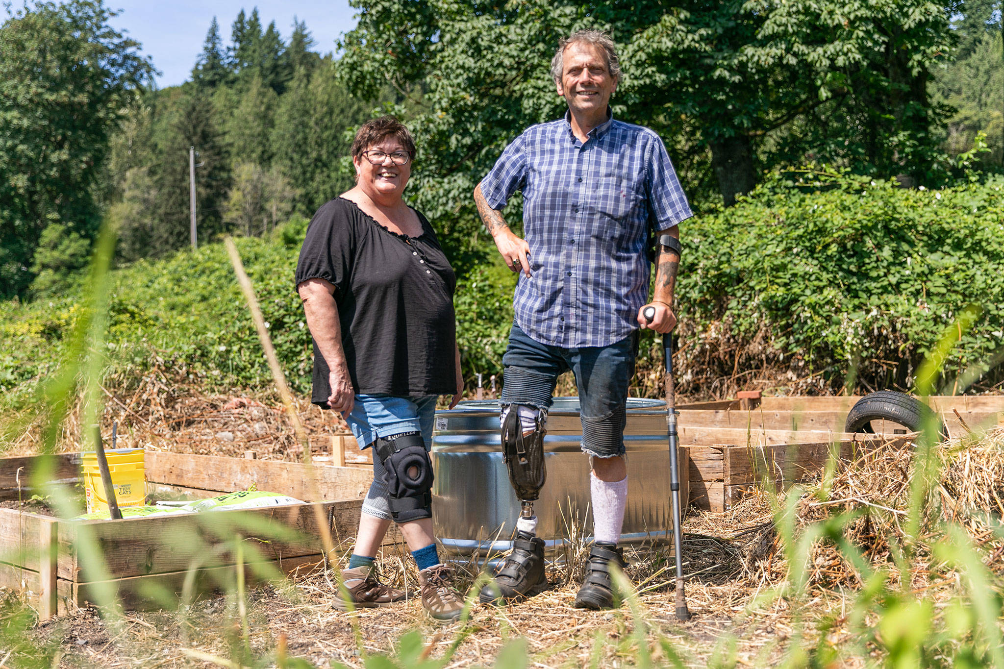 Arleen Gibson and Mike Dailey stand in the overgrown veteran garden at Hope Horses ‘N Healing, owned by Gibson, in Monroe. (Hannah Sheil / The Herald)