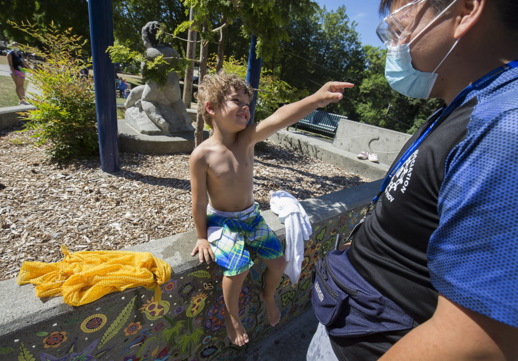 Soren Williams, 4, points at Quang Pham and says, “I love you,” after drying off from playing in the water at Forest Park in Everett. (Andy Bronson / The Herald)
