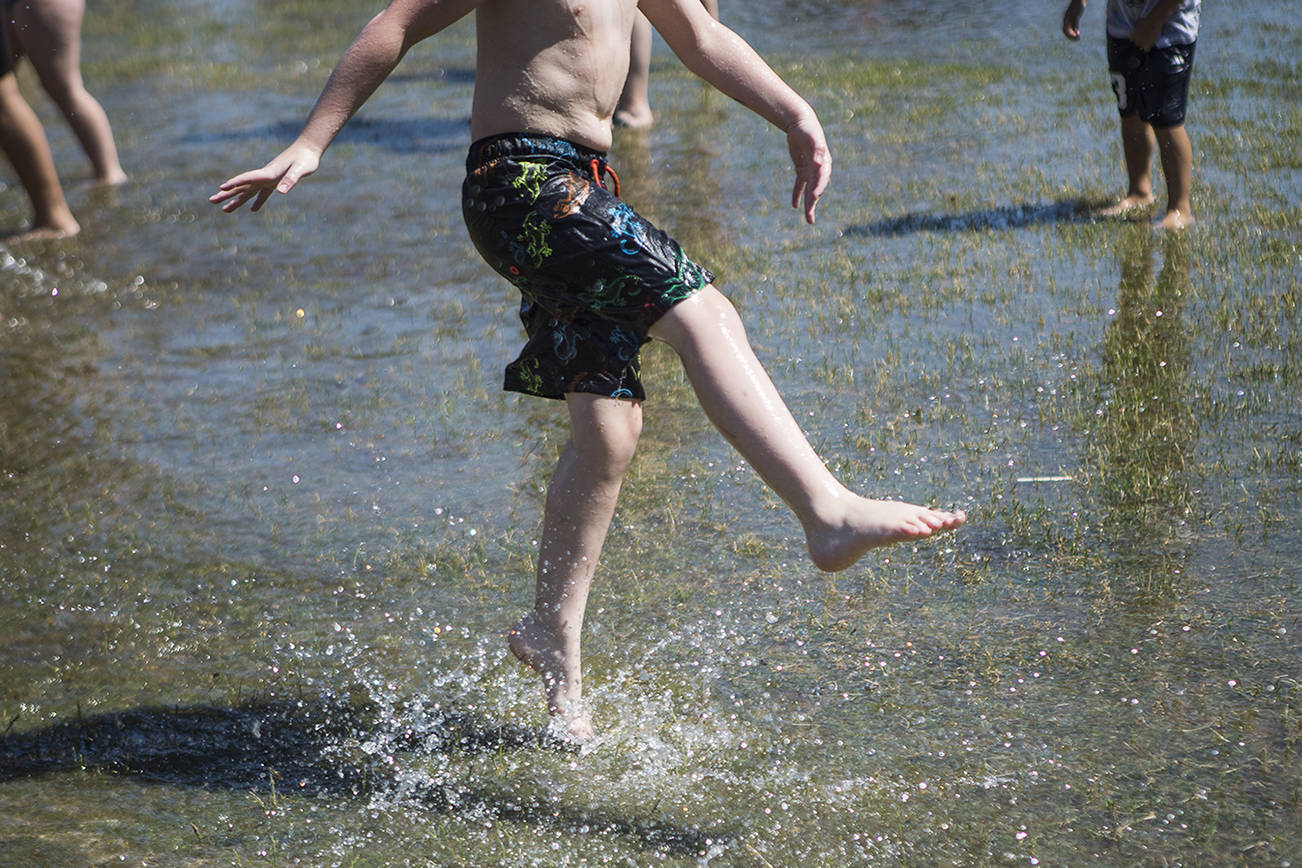 A child kicks water in a large puddle at Walter E. Hall Park on Saturday, June 26, 2021 in Everett, Wa. (Olivia Vanni / The Herald)