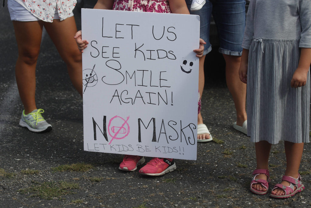 A child holds a sign on Wednesday as people gather in front of the Marysville School District office to voice their anger over mask mandates in schools. (Andy Bronson / The Herald)
