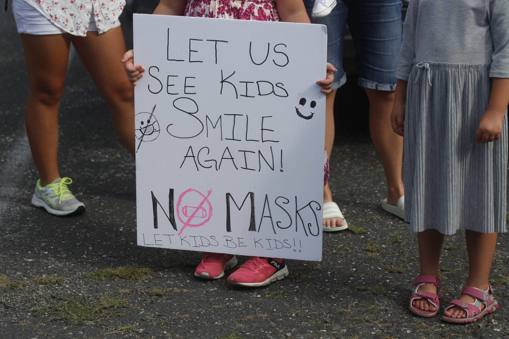A child holds a sign on Wednesday as people gather in front of the Marysville School District office to voice their anger over mask mandates in schools. (Andy Bronson / The Herald)
