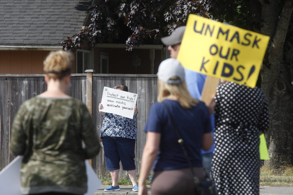 A counter-protester holds up her sign on Wednesday as about 75 adults and kids gather in front of the Marysville School District office to voice their anger over mask mandates in schools. (Andy Bronson / The Herald)
