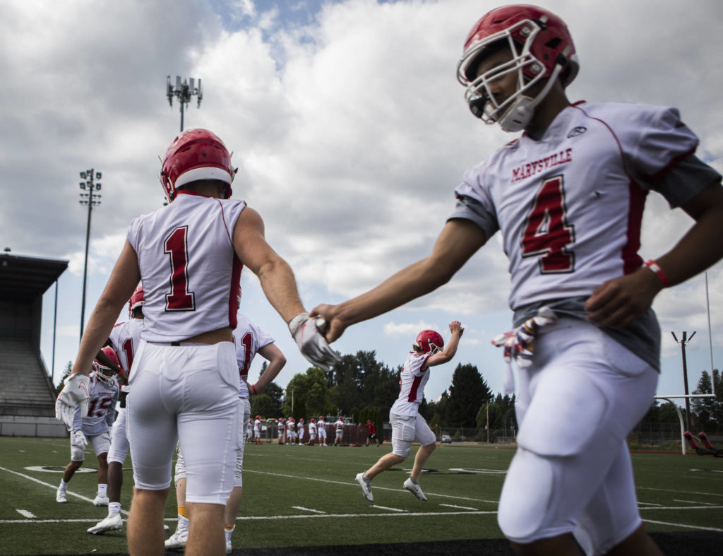 Marysville Pilchuck’s Miguel Chavez (left) high-fives Samtuala Gray during football practice on Thursday in Marysville. (Olivia Vanni / The Herald)
