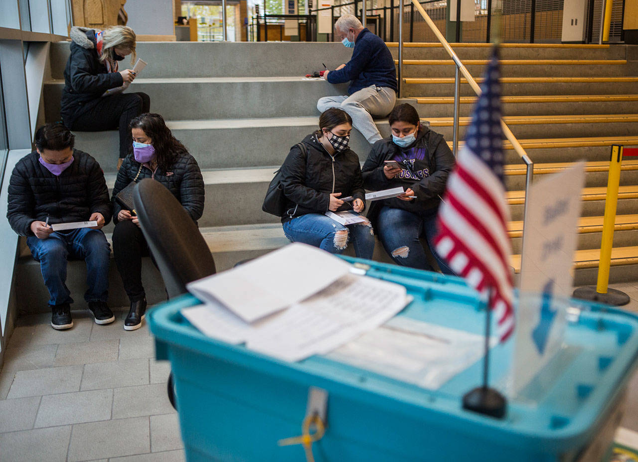 Voters sit outside a Snohomish County public meeting room to fill out and turn in their ballots on Nov. 3, 2020 in Everett. (Olivia Vanni / Herald file photo)
