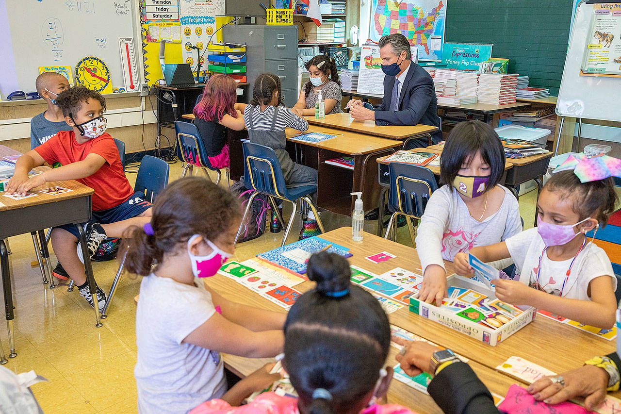California Gov. Gavin Newsom sits with students in a second grade classroom in Oakland, California. As COVID-19 cases surge, a majority of Americans say they support mask mandates for students and teachers in K-12 schools, but their views are sharply divided along political lines. (Associated Press)