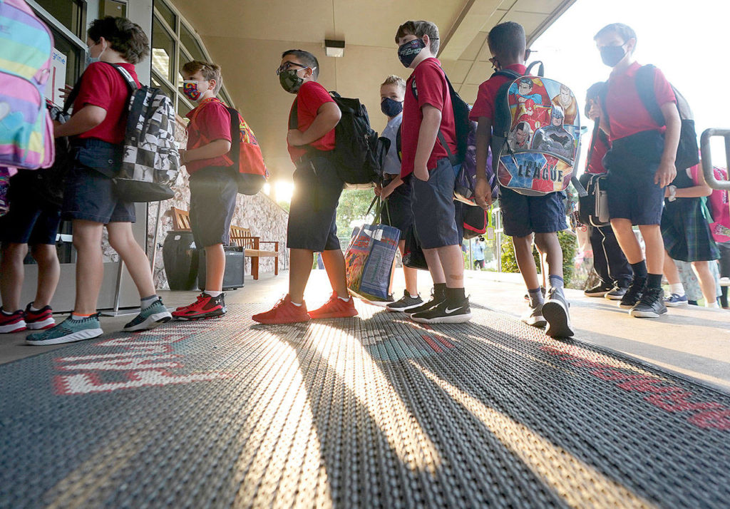 Wearing masks to prevent the spread of COVID-19, elementary school students line up to enter school for the first day of classes in Richardson, Texas. (Associated Press)
