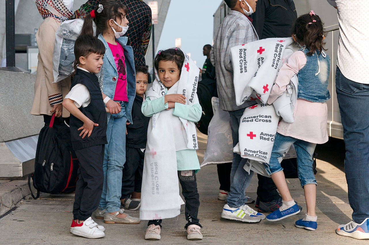 Families evacuated from Kabul, Afghanistan, wait to board a bus after they arrived at Washington Dulles International Airport, in Chantilly, Va., on Aug. 26. (Jose Luis Magana / Associated Press)