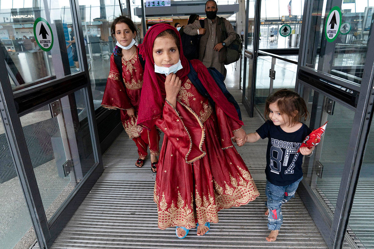 Children accompanied by their families evacuated from Kabul, Afghanistan, walk through the terminal before boarding a bus after they arrived at Washington Dulles International Airport, in Chantilly, Va., on Friday. (Jose Luis Magana / Associated Press)