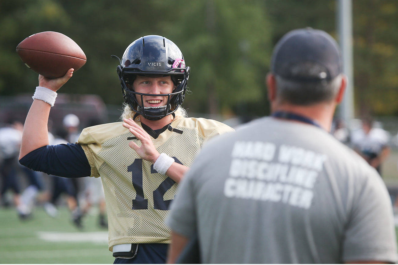 Arlington senior quarterback Trent Nobach talks with head coach Greg Dailer during practice on Tuesday, Aug. 31, 2021 in Arlington, Washington. Nobach, one of the top quarterbacks in the state, is back from injury after suffering a broken collarbone in the first game of this past spring's season. (Andy Bronson / The Herald)