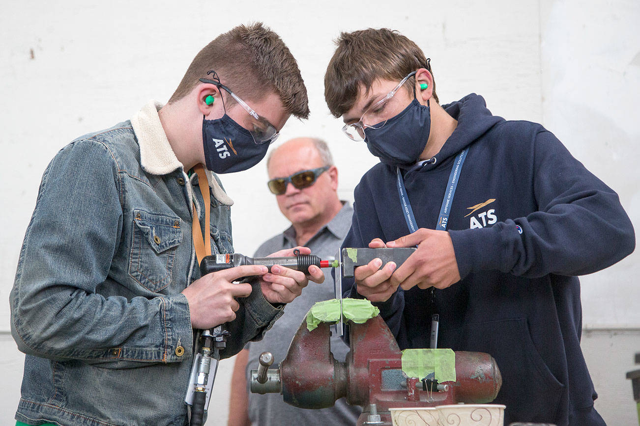 Darby O"Neil, left, and Stanislav Ryakhovskiy practice riveting as Apprentice Instructor John Kraft watches on Wednesday, July 21, 2021 in Everett, Washington. ATS, which repairs and overhauls passenger jets for Southwest Airlines and FedEx among other customers, offers a unique 18-month apprenticeship program. Once a month, ATS puts about 10 new apprentices through a orientation. (Andy Bronson / The Herald)