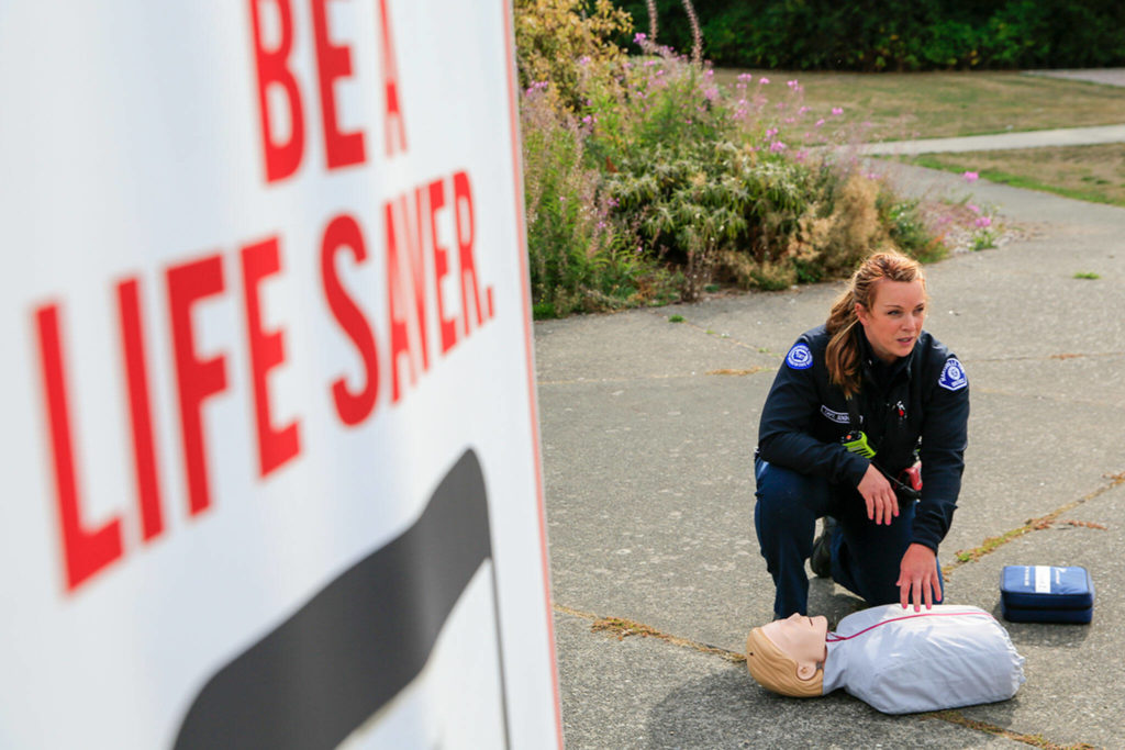 Capt. Kate Songhurst demonstrates proper CPR during the launch press briefing for the PulsePoint app Tuesday at Kasch Park in Everett. (Kevin Clark / The Herald)
