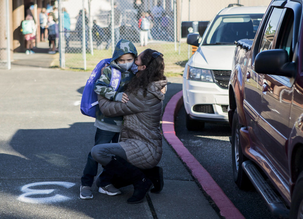 Elizabeth Panagos kisses her son, Paxton, through her mask as she drops him off for his first day of kindergarten at Mountain Way Elementary on Wednesday in Granite Falls. (Olivia Vanni / The Herald)
